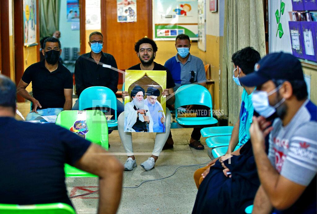 Hadi Mizban A follower of populist Shiite cleric Muqtada al-Sadr holds a picture of him while waiting with others to receive a dose of the Chinese Sinopharm coronavirus vaccine at a clinic in Sadr City, Baghdad, Iraq, Wednesday, May 4, 2021. Iraq’s vaccine rollout had been faltering for weeks. Apathy, fear and rumors kept many from getting vaccinated despite a serious surge in coronavirus infections and calls by the government for people to register for shots. It took al-Sadr’s public endorsement of vaccinations — and images of him getting the shot — to turn things around. (AP Photo/Hadi Mizban)