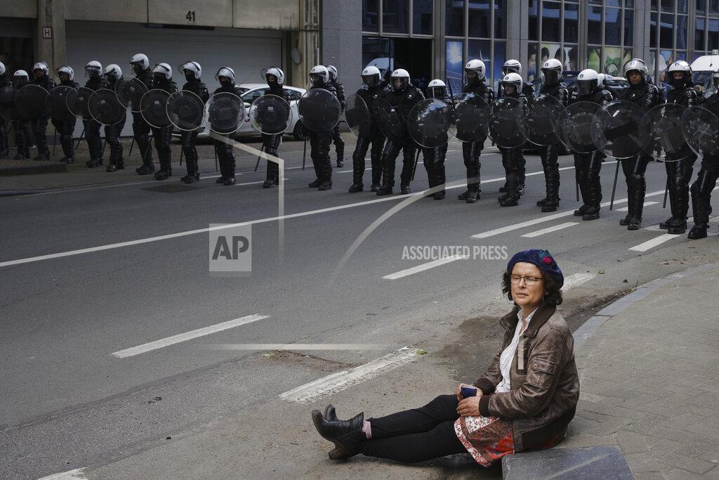 Olivier Matthys A woman sits in front of a police security line as people gather near EU headquarters during a so called "European Demonstration for Freedom and Democracy" protest against COVID-19 security measures taken by European governments, in Brussels, Saturday, May 29, 2021. (AP Photo/Olivier Matthys)