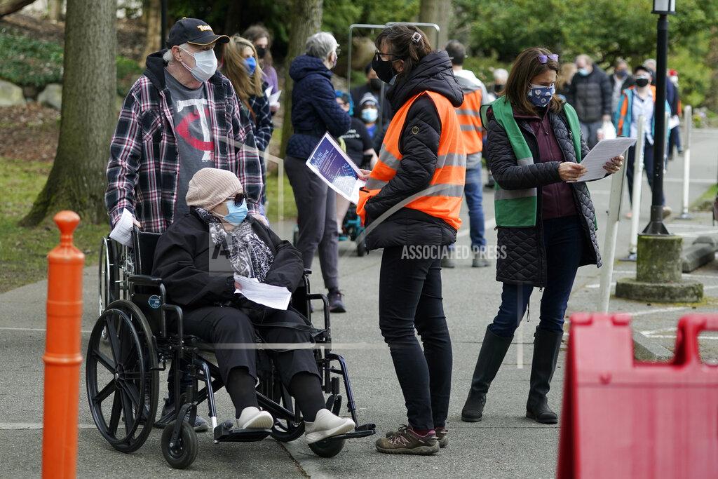 Ted S. Warren Wearing colored vests, volunteer workers talk with people in line for their appointments at a mass vaccination clinic at Seattle University, Friday, Feb. 26, 2021, in Seattle. As states ramp up vaccination distribution in the fight against the coronavirus, volunteers are needed to do everything from direct traffic to check people in to keep vaccination sites running smoothly. In return for their work, they're often given a shot — including those who are young and healthy and may not have otherwise been able to receive the shot until later in the year. (AP Photo/Ted S. Warren)