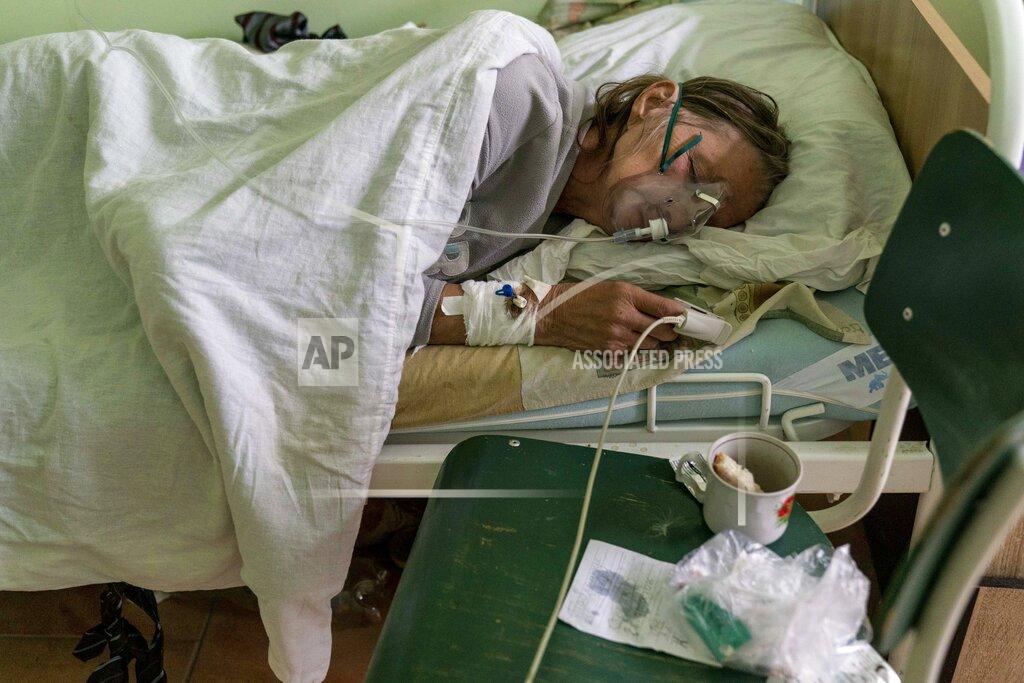 Evgeniy Maloletka A patient with coronavirus breathes with an oxygen mask in a hospital intensive care unit in Stryi, Ukraine, on Tuesday, Sept. 29, 2020. Coronavirus infections in Ukraine began surging in late summer, and the ripples are hitting towns in the western part of the country. The government wants to avoid imposing a new lockdown, but officials acknowledge that the rising infections could make it necessary. (AP Photo/Evgeniy Maloletka)