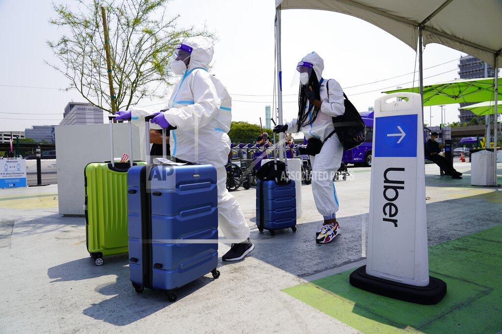 FILE - Travelers, Kerri Ann Salomon, left, and a friend arriving from New York City, look for an Uber ride at Los Angeles InternationalAirport, in this Thursday, Aug. 20, 2020, file photo. Uber is trying to lure drivers with sign-up bonuses and other incentives as it faces record demand for rides and meal delivery. The San Francisco-based ride-hailing company said Monday, April 12, 2021, that its bookings reached an all-time monthly high in March. (AP Photo/Damian Dovarganes, File)