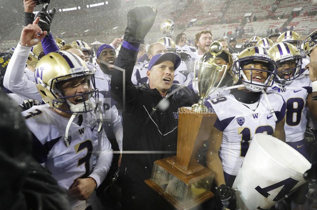 Ted S. Warren Washington coach Chris Petersen, center, holds the Apple Cup trophy as he celebrates with quarterback Jake Browning, left, and the rest of the team after Washington defeated Washington State 28-15 in an NCAA college football game Friday, Nov. 23, 2018, in Pullman, Wash. (AP Photo/Ted S. Warren)