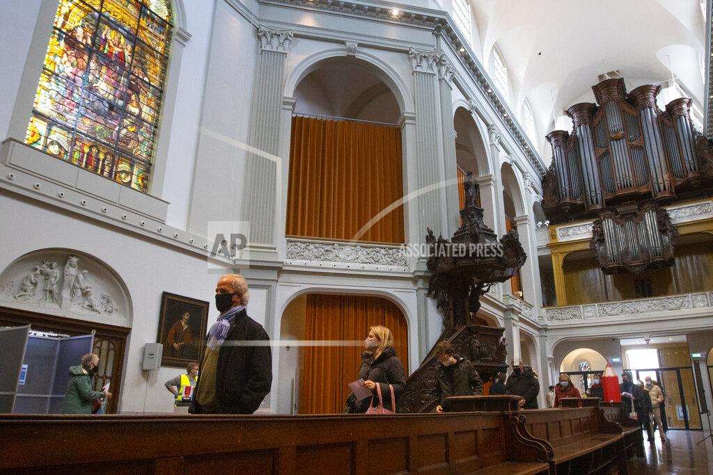 Peter Dejong Voters queue to cast their ballot at a polling station in church De Duif in Amsterdam, Netherlands, Monday, March 15, 2021. Polling stations opened across the Netherlands early Monday in a general election that has been spread over three days to allow people to vote safely during the coronavirus pandemic. (AP Photo/Peter Dejong)