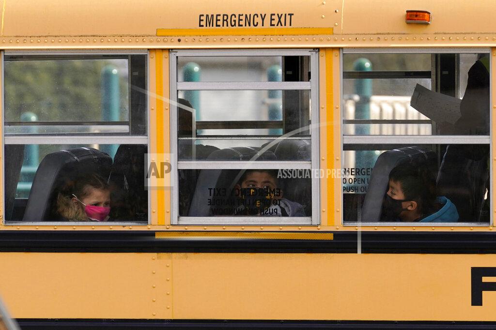 FILE - In this Thursday, Nov. 19, 2020, file photo, elementary school students sit on board a school bus after attending in-person classes at school in Wheeling, Ill. The latest federal relief package includes $81 billion that began flowing to states in late March 2021 with the goal of helping schools reopen quickly. The only problem is many of the school districts' current problems can't be solved by money. (AP Photo/Nam Y. Huh, File)