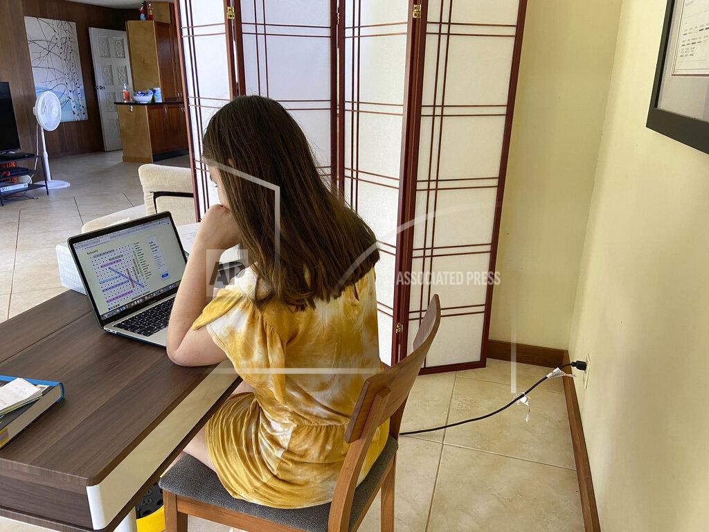 FILE - This file photo provided by Adrienne Robillard shows her daughter, name withheld by parent, doing school work at a computer at home in Kailua, Hawaii, Friday, Sept. 18, 2020. Hawaii's Department of Education is recommending that the state's public schools stop using a distance learning program that parents said had contained racist and sexist content. Schools across the nation have been using Acellus for distance learning and some have dropped the program after parent complaints. (Adrienne Robillard via AP, File)