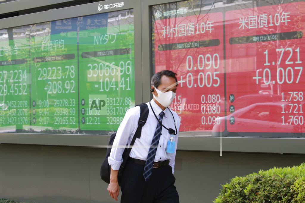 Koji Sasahara A man walks by an electronic stock board of a securities firm in Tokyo, Wednesday, March 31, 2021. Asian shares were mixed Wednesday as data showed a strong economic recovery in China but worries lingered about the coronavirus pandemic. (AP Photo/Koji Sasahara)
