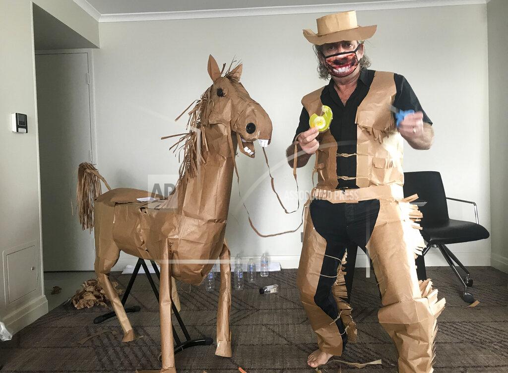 David Marriott CORRECTS NAME - David Marriott poses with his paper horse "Russell" in his hotel room in Brisbane, Australia, April 1, 2021. While in quarantine inside his Brisbane hotel room, the art director was bored and started making a cowboy outfit from the paper bags his meals were being delivered in. His project expanded to include a horse and a clingfilm villain that he has daily adventures with, in images that have gained a huge online following. (David Marriott via AP)