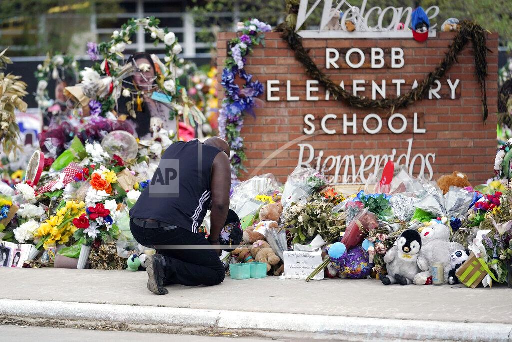 Eric Gay FILE - Reggie Daniels pays his respects at a memorial at Robb Elementary School in Uvalde, Texas, on June 9, 2022, honoring the two teachers and 19 students killed in the shooting at the school on May 24. For families fractured along red house-blue house lines, summer’s slate of reunions and weddings poses another round of tension. Pandemic restrictions have melted away but gun control, the fight for reproductive rights, the Jan. 6 insurrection hearings, who's to blame for soaring inflation and a range of other issues continue to simmer. (AP Photo/Eric Gay, File)