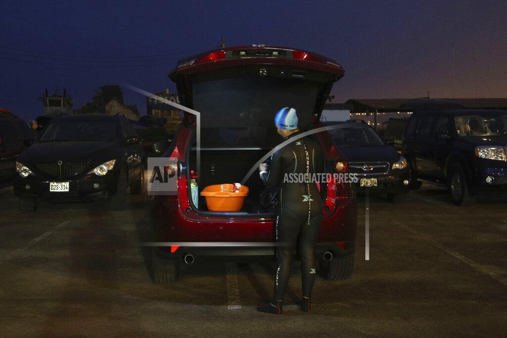 Martin Mejia An open water swimmer gets ready by her car on Pescadores beach where swimming in the sea is booming while pools are closed due to the COVID-19 pandemic in Lima, Peru, before sunrise Tuesday, April 27, 2021. One of the few sporting disciplines that have been maintained during the coronavirus pandemic is swimming, which due to the closure of the swimming pools, has moved to the open sea. (AP Photo/Martin Mejia)