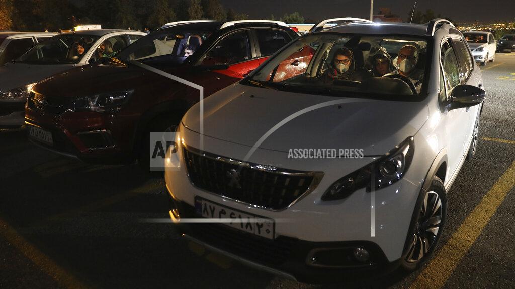 People sit in their cars watching a movie at a new drive-in cinema on a car parking area of the Milad telecommunications tower, as regular theaters are closed due to the coronavirus outbreak, Friday, May 1, 2020. Iran is the region's epicenter of the COVID-19 pandemic. (AP Photo/Vahid Salemi)
