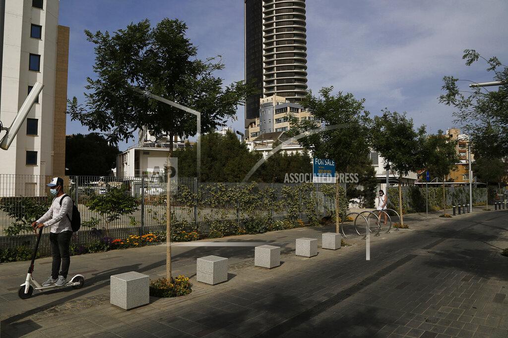 Petros Karadjias A man, left, with a skate and a woman, right, wearing protective face masks pass at an empty road amid COVID-19 pandemic restrictions government in central capital Nicosia, Cyprus, Thursday, May 6, 2021. Cyprus has unveiled a phased rollback of COVID-19 lockdown restrictions over the next month including a shortened curfew and a reopening of all schools next week, but will enforce the compulsory display of proof of vaccination, virus testing or convalescence from the disease in areas were people gather in numbers, including restaurants and churches. (AP Photo/Petros Karadjias)
