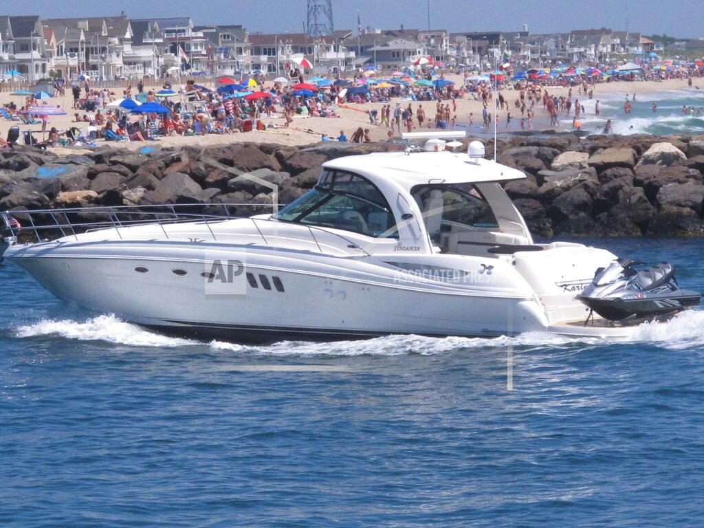 A yacht cruises through the Manasquan Inlet as a large crowd fills the beach in Manasquan, N.J. on June 28, 2020. With large crowds expected at the Jersey Shore for the July Fourth weekend, some are worried that a failure to heed mask-wearing and social distancing protocols could accelerate the spread of the coronavirus. (AP Photo/Wayne Parry)