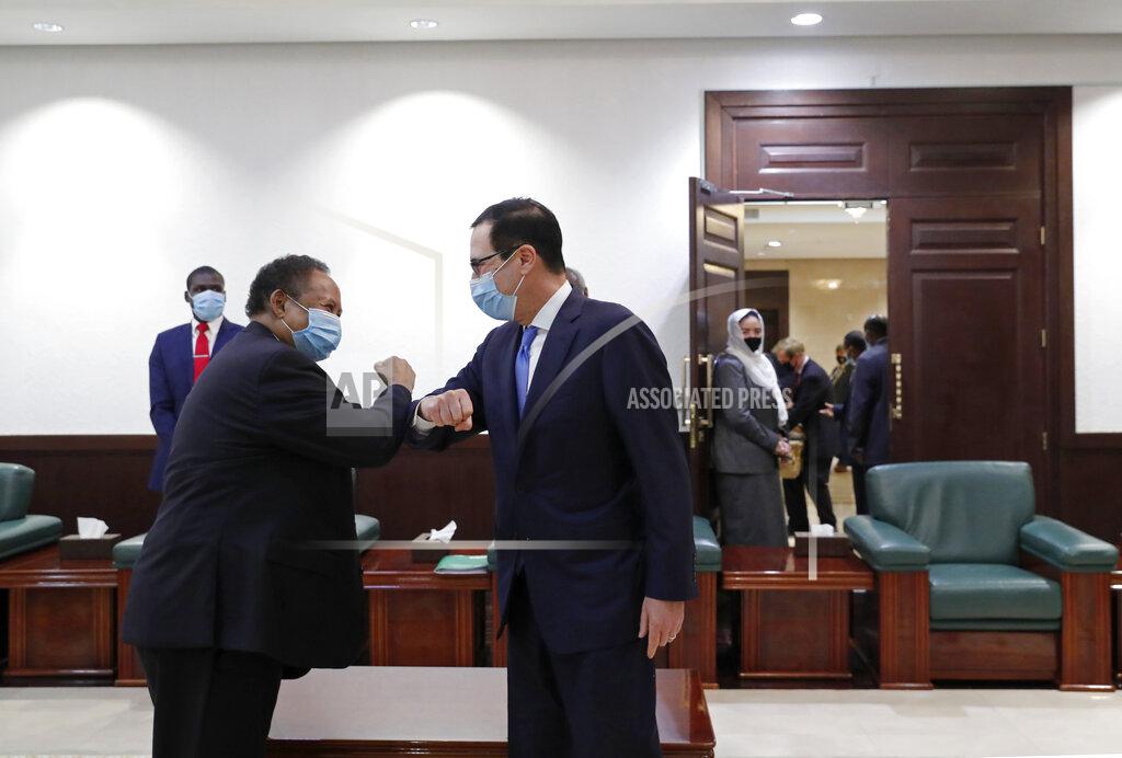 Uncredited CORRECTS NAME TO STEVEN MNUCHIN ADDS DETAILS - Sudanese Prime Minister Abdullah Hamdok, left, elbow bumps as he welcomes US Treasury Secretary Steven Mnuchin to the Cabinet Building, in Khartoum, Sudan, Wednesday, Jan. 6, 2021. The U.S. and Sudan have agreed to settle the African country's debt to the World Bank. The move comes after Mnuchin arrived in Sudan, the first visit by a senior American official since President Donald trump removed Sudan from the list of state sponsors of terrorism. (AP Photo)