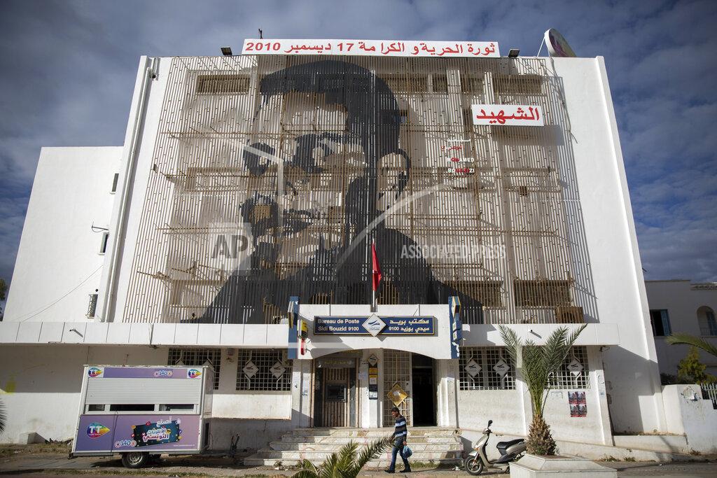 Riadh Dridi Mohammed Bouazizi is depicted on the facade of post office in Sidi Bouzid, Tunisia, on Friday Dec.11, 2020. Hundreds of desperate Tunisians have set themselves on fire over the past 10 years in an act of protest, following the example of Bouazizi, whose self-immolation in 2010 led to the downfall of Tunisia’s dictator of 23 years. His public suicide unleashed the Arab Spring uprisings and a decade of crackdowns and civil wars across the region. (AP Photo/Riadh Dridi)