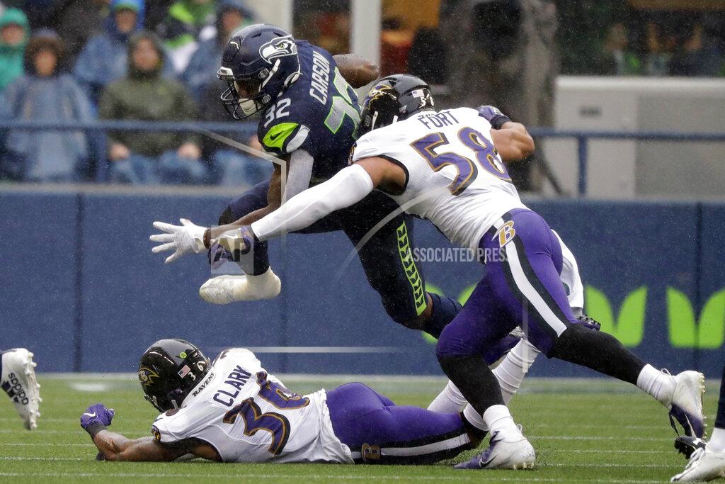 Elaine Thompson Seattle Seahawks running back Chris Carson (32) leaps over Baltimore Ravens defensive back Chuck Clark, lower left, and tries to avoid Ravens' L.J. Fort (58) during the first half of an NFL football game, Sunday, Oct. 20, 2019, in Seattle. (AP Photo/Elaine Thompson)