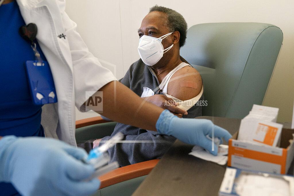 Jacquelyn Martin In this Wednesday, Feb. 10, 2021, photo the Rev. James Coleman, 70, finishes receiving his first COVID-19 vaccination by nurse practitioner Ifreke Udodong, at United Medical Center in southeast Washington. (AP Photo/Jacquelyn Martin)