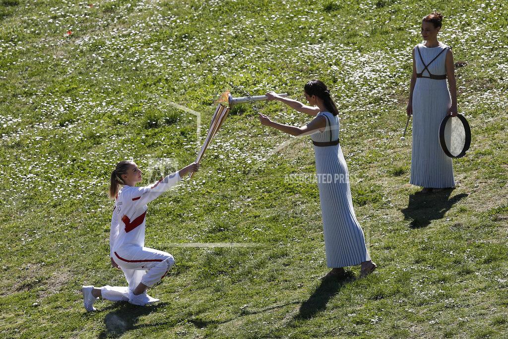Yorgos Karahalis Greek actress Xanthi Georgiou, center, playing the role of the High Priestess, lights the torch of the 2020 Tokyo Olympic Games, held by Greek shooting Olympic champion Anna Korakaki, left, the first torchbearer, during the flame lighting ceremony at the closed Ancient Olympia site, birthplace of the ancient Olympics in southern Greece, Thursday, March 12, 2020, 2020. Greek Olympic officials are holding a pared-down flame-lighting ceremony for the Tokyo Games due to concerns over the spread of the coronavirus. Both Wednesday's dress rehearsal and Thursday's lighting ceremony are closed to the public, while organizers have slashed the number of officials from the International Olympic Committee and the Tokyo Organizing Committee, as well as journalists at the flame-lighting. (AP Photo/Yorgos Karahalis)