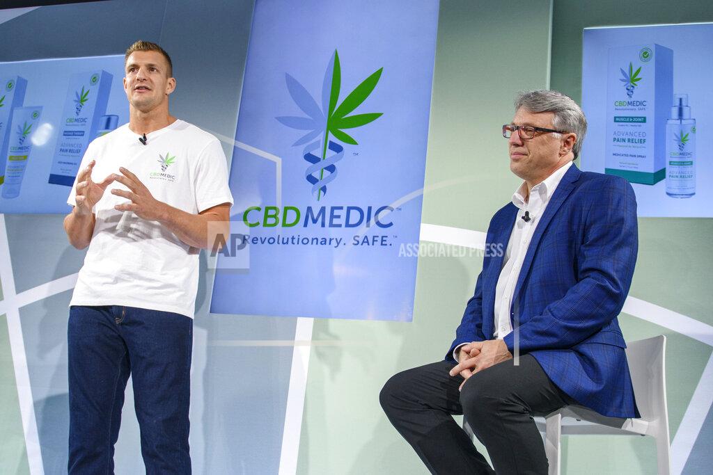 Corey Sipkin FILE - In this Aug. 27, 2019, file photo, former New England Patriots tight end Rob Gronkowski, left, speaks as Perry Antelman, CEO of Abacus Health Products, listens during a news conference announcing in New York. The home of the New England Patriots has a new sponsorship deal with Abacus Health Products that will put the cannabidiol company's hemp leaf logo on a water tower looming over the stadium and on a sign overlooking an entrance. (AP Photo/Corey Sipkin, File)