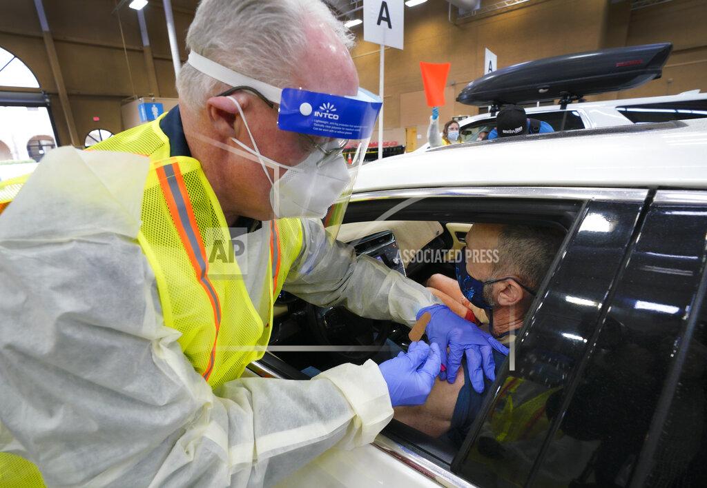 Nelvin C. Cepeda Chris Van Gorder, Scripps Health CEO, inoculated Christian Dollahon, 66 from Oceanside with the Pfizer vaccine at the Del Mar Fairgrounds on Friday, Feb. 12, 2021, in Del Mar, Calf. On Friday, Scripps officially opened their new drive-thru site at Del Mar Fairgrounds. (Nelvin C. Cepeda/The San Diego Union-Tribune via AP, Pool)