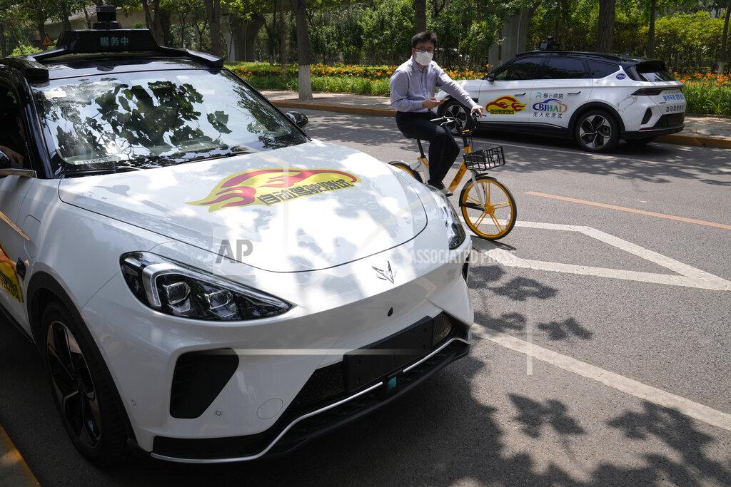 Ng Han Guan A man on a bicycle rides past self-driving taxis developed by tech giant Baidu Inc. on June 14, 2022, in Beijing. Baidu Inc. is China's highest-profile competitor in a multibillion-dollar race with Alphabet Inc.'s Waymo and General Motors Co.'s Cruise to create self-driving cars. (AP Photo/Ng Han Guan)