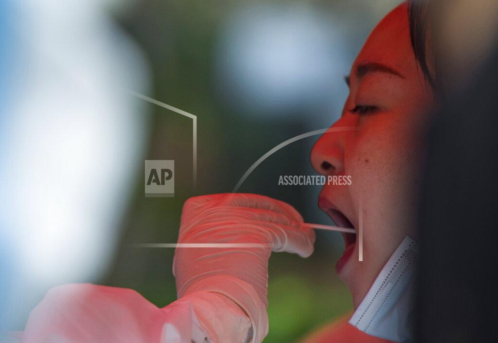Uncredited A woman receive a throat swab during mass testing for COVID-19 in Wuhan in central China's Hubei province Tuesday, Aug. 3, 2021. The coronavirus’s delta variant is challenging China’s costly strategy of isolating cities, prompting warnings that Chinese leaders who were confident they could keep the virus out of the country need a less disruptive approach.(Chinatopix via AP)