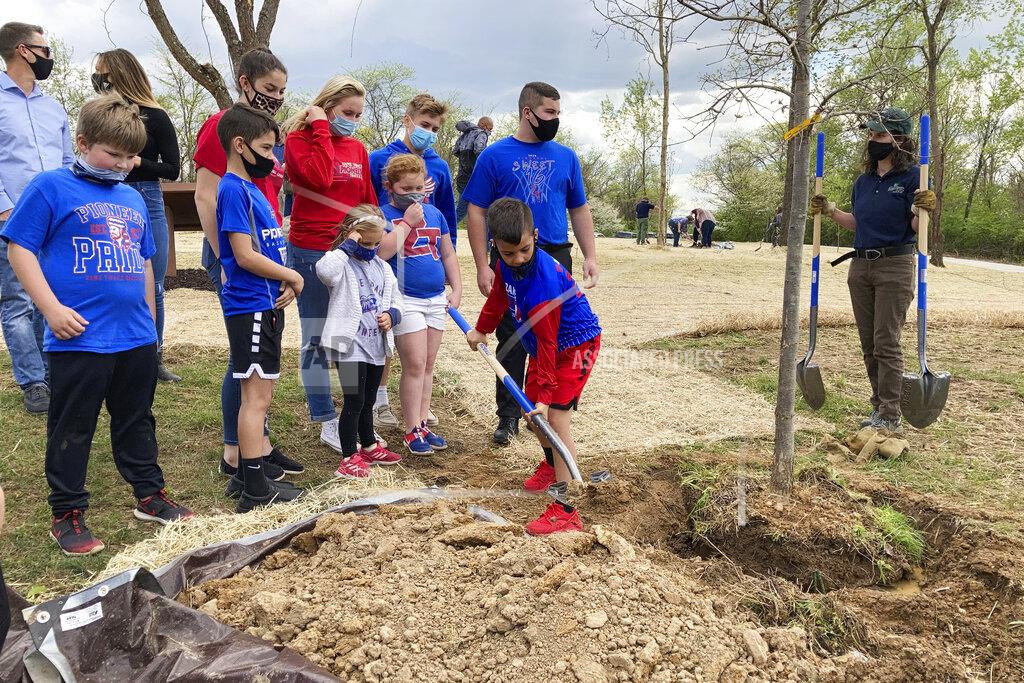 Julie Carr Smyth Educators and schoolchildren plant one of the trees at the dedication of Ohio's COVID-19 Pandemic Memorial Grove at Great Seal State Park near Chillicothe, Ohio, on April 30, 2021. A memorial grove to COVID-19 victims has been planted and governors and lawmakers elsewhere are pursuing similar permanent remembrances. (AP Photo/Julie Carr Smyth)