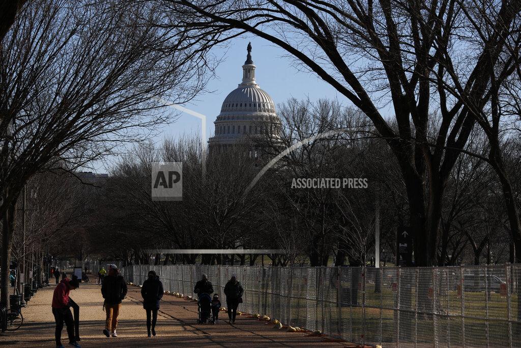 People stroll past a section of the National Mall by the Capitol where workers were still dismantling inauguration installations, after most downtown streets and public spaces had reopened to the public, on Saturday, Jan. 23, 2021 in Washington. Biden is looking to jump-start his first 100 days in office with action and symbolism to reassure a divided and weary public that help is in the offing. (AP Photo/Rebecca Blackwell)