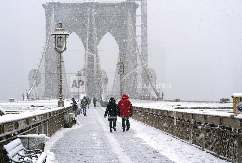 Kathy Willens People make their way across the Brooklyn Bridge during the second snowstorm to buffet the area in less than a week, Sunday, Feb. 7, 2021, in New York. (AP Photo/Kathy Willens)