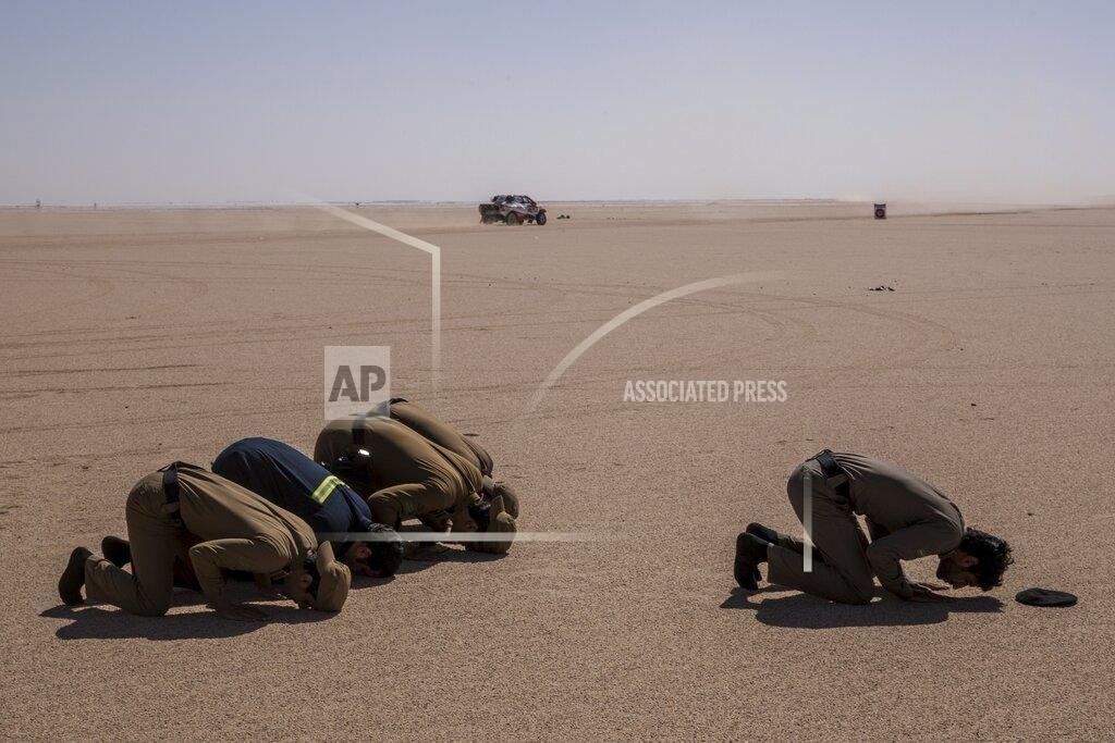 Bernat Armangue In this Sunday, Jan. 12, 2020 photo, Saudi Arabia security forces pray while a care races during stage seven of the Dakar Rally between Riyadh and Wadi Al Dawasir, Saudi Arabia. Formerly known as the Paris-Dakar Rally, the race was created by Thierry Sabine after he got lost in the Libyan desert in 1977. Until 2008, the rallies raced across Africa, but threats in Mauritania led organizers to cancel that year's event and move it to South America. It has now shifted to Saudi Arabia. The race started on Jan. 5 with 560 drivers and co-drivers, some on motorbikes, others in cars or in trucks. Only 41 are taking part in the Original category. (AP Photo/Bernat Armangue)