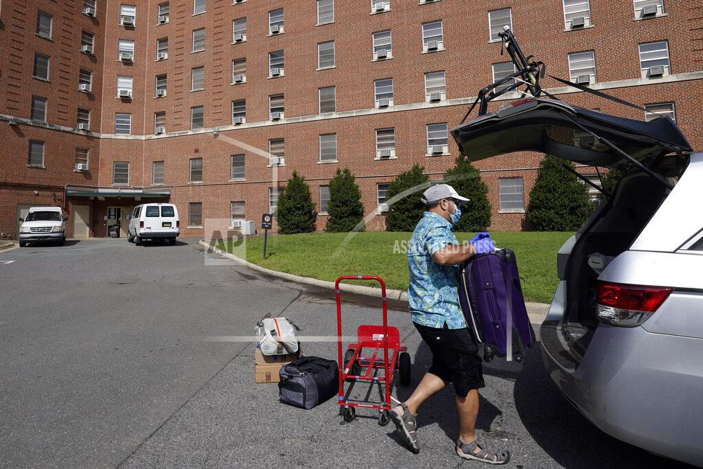 A parent packs a student's belongings at Ehringhaus dormitory following a cluster of COVID-19 cases on campus at the University of North Carolina in Chapel Hill, N.C., Tuesday, Aug. 18, 2020. The university announced that it would cancel all in-person undergraduate learning starting on Wednesday causing some students to pack and leave. (AP Photo/Gerry Broome)