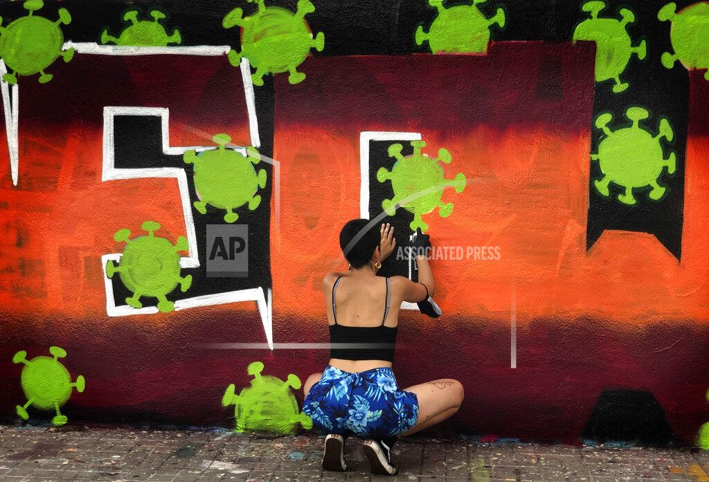 Emilio Morenatti An artist sprays paints a wall with topic about the Coronavirus in Barcelona, Spain, Thursday, Aug. 13, 2020. Spain's daily number of new COVID-19 cases has shot up, with almost 2,935 officially reported Thursday compared with 1,690 the previous day. (AP Photo/Emilio Morenatti)