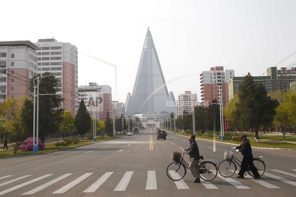 Cha Song Ho People wearing face masks cross a road in front of the Ryugyong Hotel in Pyongyang, North Korea Tuesday, April 28, 2020. (AP Photo/Cha Song Ho)