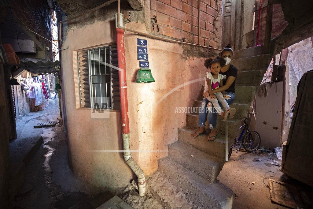 Andre Penner Ana Carolina Silva, who lost her job during the COVID-19 pandemic, sits with her daughter Cataleia outside her home in the Paraisopolis favela of Sao Paulo, Brazil, Monday, May 24, 2021. (AP Photo/Andre Penner)