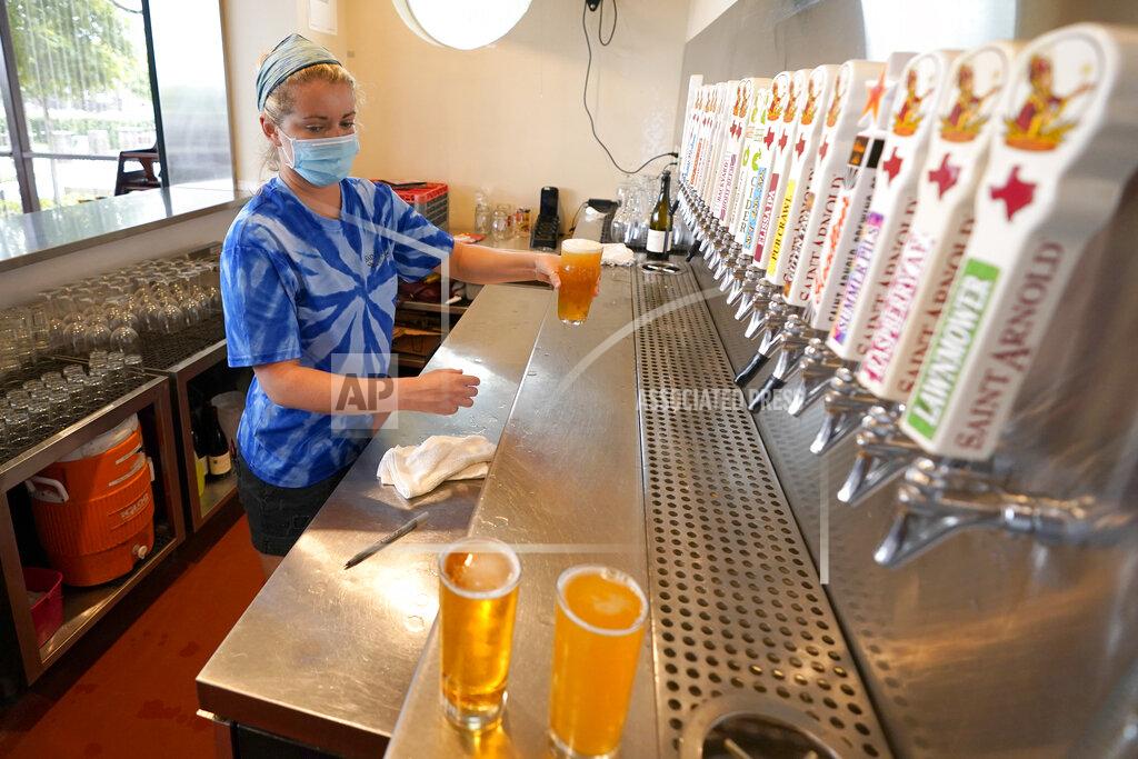 David J. Phillip Bartender Katie McGranahan pours beers at the Saint Arnold Brewing Company, Friday, June 26, 2020, in Houston. Texas Gov. Greg Abbott announced Friday that he is shutting bars back down and scaling back restaurant capacity to 50%, in response to the increasing number of COVID-19 cases in Texas. (AP Photo/David J. Phillip)