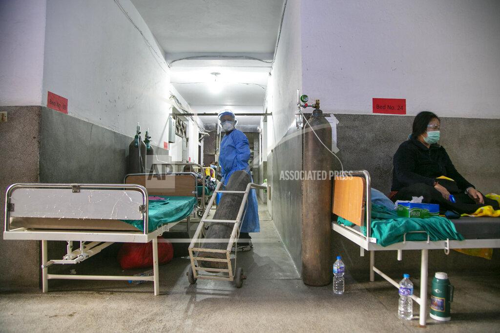 Niranjan Shrestha A Nepalese paramedic wheels in an oxygen cylinder as a COVID-19 patient rests on a bed in the corridor of a government run hospital in Kathmandu, Nepal, Friday, May 7, 2021. Across the border from a devastating surge in India, doctors in Nepal warned Friday of a major crisis as daily coronavirus cases hit a record and hospitals were running out of beds and oxygen. (AP Photo/Niranjan Shrestha)