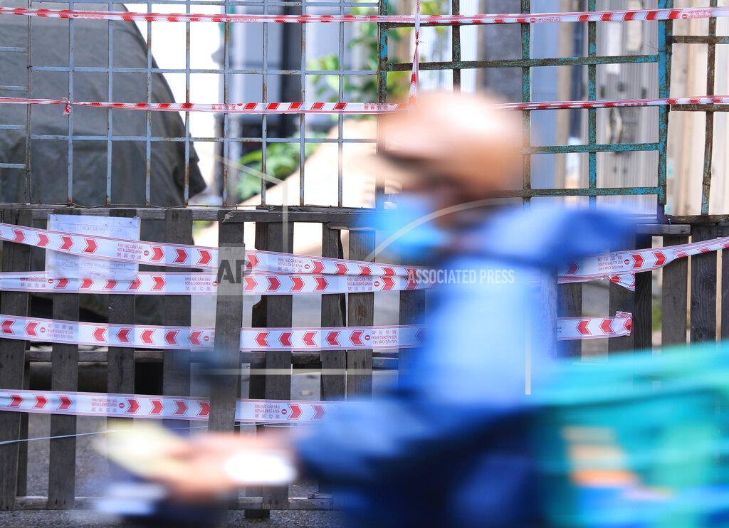 Hau Dinh A man rides scooter past a barricaded alley in Vung Tau, Vietnam, Monday, Sept. 20, 2021. The roadblocks and barricades make the streets of this southern Vietnamese city look like they did during the war that ended almost 50 years ago. But this time, the battle is being fought against the rampaging coronavirus. (AP Photo/Hau Dinh)