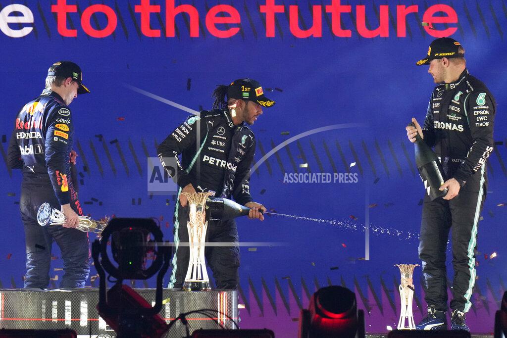 Hassan Ammar Mercedes driver Lewis Hamilton of Britain celebrates at the podium after winning the Formula One Saudi Arabian Grand Prix in Jiddah, Sunday, Dec. 5, 2021. Left is second placed Red Bull driver Max Verstappen of the Netherlands and Ron the right is third, Mercedes driver Valtteri Bottas of Finland. (AP Photo/Hassan Ammar)