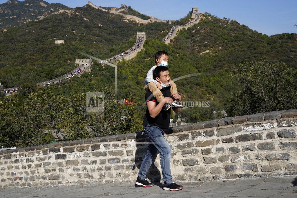 Ng Han Guan A man carries a child up a stretch of the Badaling Great Wall of China on the outskirts of Beijing on Tuesday, Oct. 6, 2020. Chinese tourists took 425 million domestic trips in the first half of the eight-day National Day holiday, generating $45.9 billion in tourism revenue, according to China's ministry of culture and tourism. The holiday this year, which coincides with the Mid-Autumn Festival, will be a litmus test of whether China's tourism industry can bounce back after being battered by COVID-19. (AP Photo/Ng Han Guan)