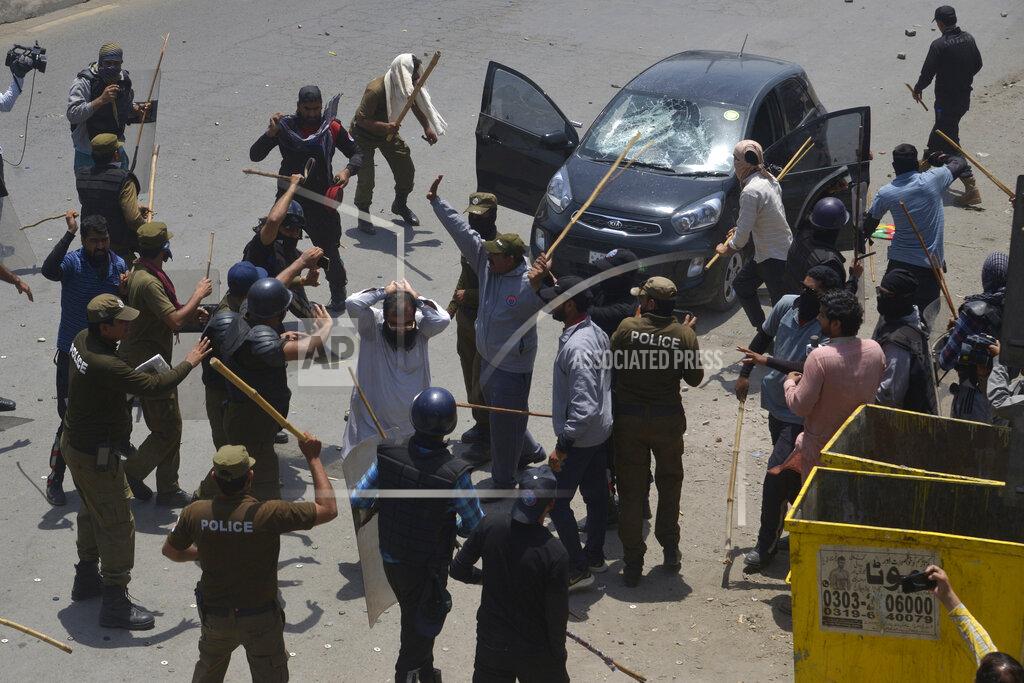 K.M. Chaudary Police officers beat a supporter of Pakistan's key opposition party protester during a march toward Islamabad, in Lahore, Pakistan, Wednesday, May 25, 2022. Pakistani authorities blocked off all major roads into the capital Islamabad on Wednesday, after a defiant former Prime Minister Imran Khan said he would march with demonstrators to the city center for a rally he hopes will bring down the government and force early elections. (AP Photo/K.M. Chaudary)