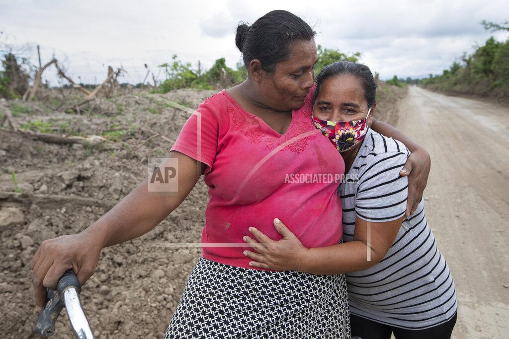Moises Castillo Xiomara Cruz, right, and Melinda Martínez reunite for the first time since last year's hurricanes Eta and Iota on the route to a banana plantation where they worked before last year's storms destroyed the area in La Lima, on the outskirts of San Pedro Sula, Honduras, Wednesday, Jan. 13, 2021. The devastation wrought by November's hurricanes and the economic damage of the COVID-19 pandemic has added to the forces of poverty and gang violence that drive Hondurans to migrate. (AP Photo/Moises Castillo)