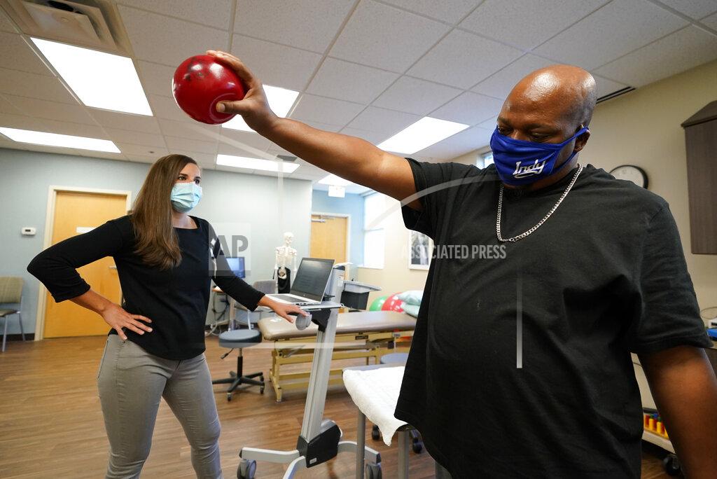 Darron Cummings Emily Smith watches as Larry Brown lifts a weighted ball during an occupational therapy session at Community Health Network, Thursday, Aug. 20, 2020, in Indianapolis. He didn’t die of COVID-19, but he’s coming to terms with the fact that his life might never be the same. (AP Photo/Darron Cummings)