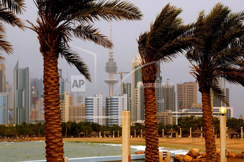 Uncredited FILE- In this April 16, 2009 file photo, the Kuwait city skyline is seen through the haze of a sand storm in Kuwait City. Kuwait, one of the world’s wealthiest countries, is facing a debt crisis. The pandemic has sent the price of oil crashing to all-time lows and pushed Kuwait toward a reckoning with its longtime largesse for its citizens just as a parliamentary election looms in Dec. 2020. It needs the new parliament to approve raising its debt spending and passing the bill will be the first legislative challenge for Kuwait's new emir. (AP Photo, File)