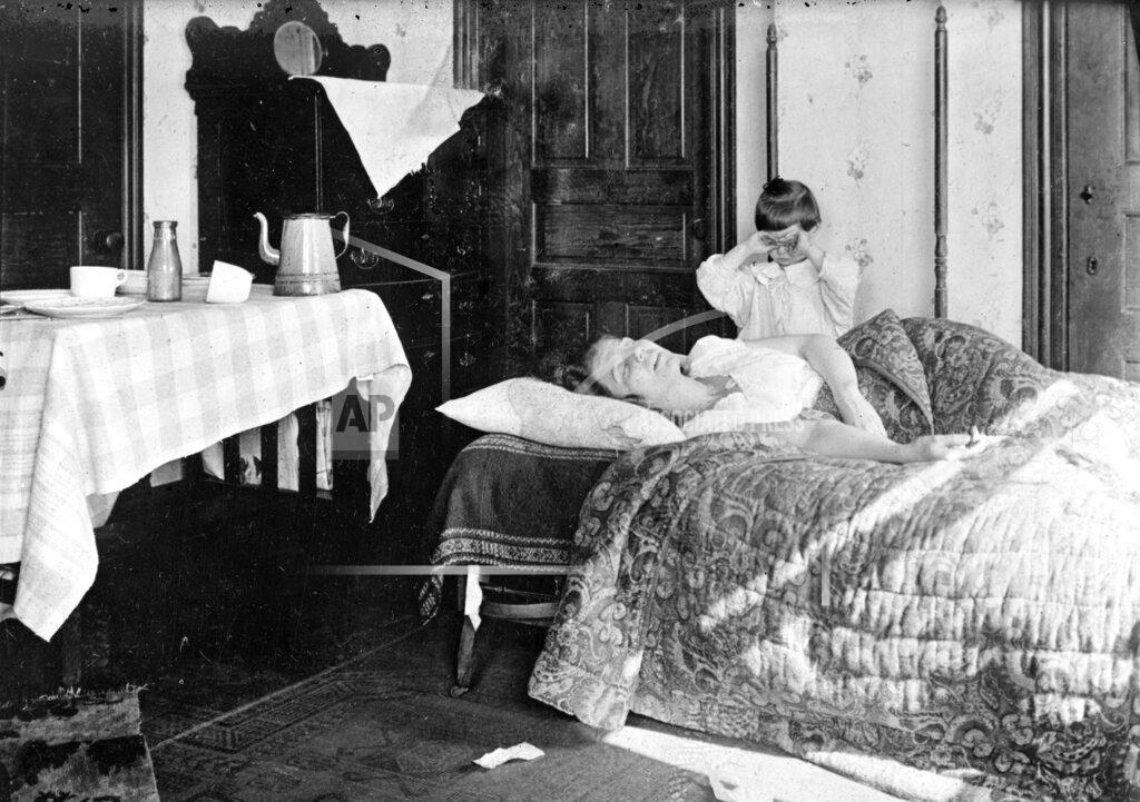 Library Of Congress; The Crowley Company FILE - In this November 1918 photo made available by the Library of Congress, a girl stands next to her sister lying in bed. The girl became so worried she telephoned the Red Cross Home Service who came to help the woman fight the influenza virus. (Library of Congress via AP, File)