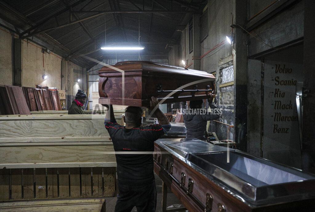 Esteban Felix Cesar Ambrosio helps his father carry a coffin at the Bergut Funeral Services factory in Santiago, Chile, Thursday, June 18, 2020. Coffin production has had to increase up to 120%, according to Nicolas Bergerie, owner of the factory. His more basic coffin model is called the COVID model and is made to cope with the increase of deaths during the coronavirus pandemic. (AP Photo/Esteban Felix)