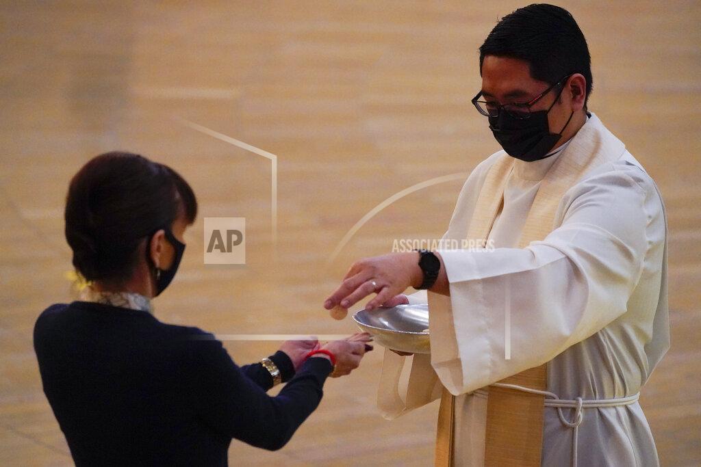 Ashley Landis A woman receives communion during a Christmas Eve Mass inside the Cathedral of Our Lady of the Angels Thursday, Dec 24, 2020, in Los Angeles. California became the first state to record 2 million confirmed coronavirus cases, reaching the milestone on Christmas Eve as nearly the entire state was under a strict stay-at-home order and hospitals were flooded with the largest crush of cases since the pandemic began. (AP Photo/Ashley Landis)