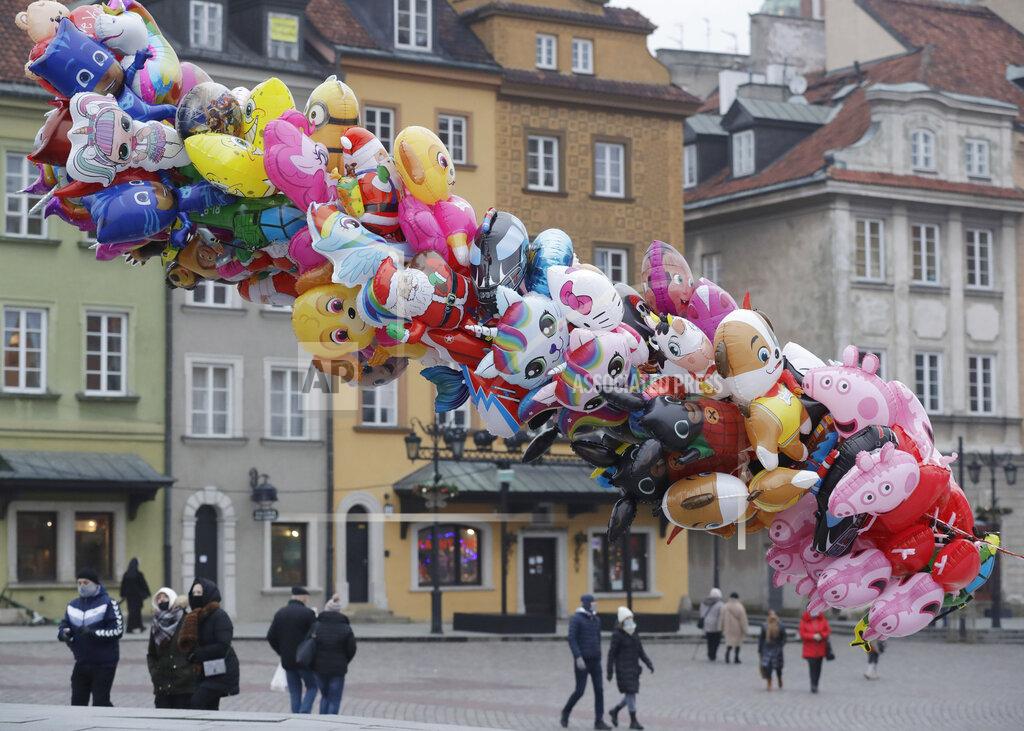 Czarek Sokolowski A balloon vendor waits for customers in usually bustling Warsaw's Castle Square that has few people now under anti-COVID-19 restrictions on New Year's Eve, in Warsaw, Poland, Thursday, Dec. 31, 2020.(AP Photo/Czarek Sokolowski)