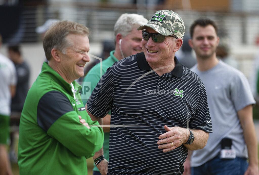 Sholten Singer Marshall head coach Doc Holliday, right, laughs with associate athletics director David Steele as players participate in the OnBikes Player Build as part of a Gasparilla Bowl NCAA college football event Friday, Dec. 20, 2019, at Curtis Hixon Park in Tampa, Fla. (Sholten Singer/The Herald-Dispatch via AP)