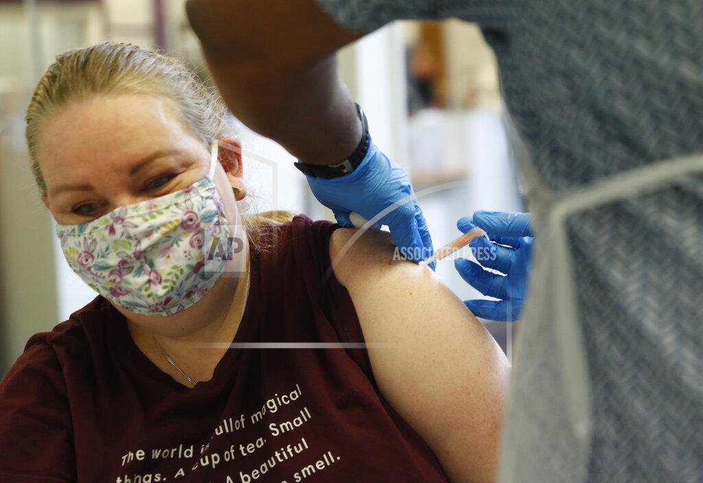Alastair Grant A woman at the Wheatfield surgery is given a 1st shot of the AstraZeneca COVID-19 vaccine by Dr Christian Owusu-Yianoma in Luton, England, Thursday, March 18, 2021. (AP Photo/Alastair Grant)