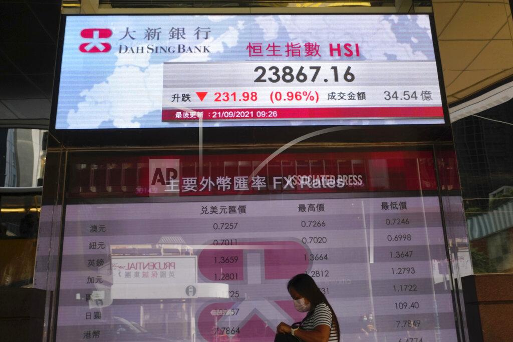 Vincent Yu A woman walks past a bank's electronic board showing the Hong Kong share index at Hong Kong Stock Exchange in Hong Kong Tuesday, Sept. 21, 2021. Asian shares declined Tuesday, with Tokyo down 2% as worries about heavily indebted Chinese real estate developers weighed on sentiment. (AP Photo/Vincent Yu)