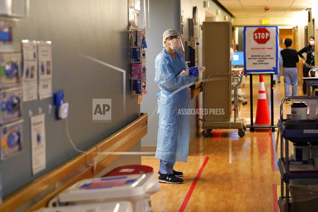 Elaine Thompson Registered nurse Diane Miller stands in the "hot zone," defined by red tape on the floor, as she waits to exchange equipment with a colleague who will remain on the other side of the tape in the COVID acute care unit at UW Medical Center-Montlake, Tuesday, Jan. 26, 2021, in Seattle. King County, where the hospital is located, has been on a downward trend of COVID-19 cases after two-and-a-half straight months of increases. But the current lull could be, and some experts believe will be, upended as more contagious variants of the virus spread throughout United States. (AP Photo/Elaine Thompson)